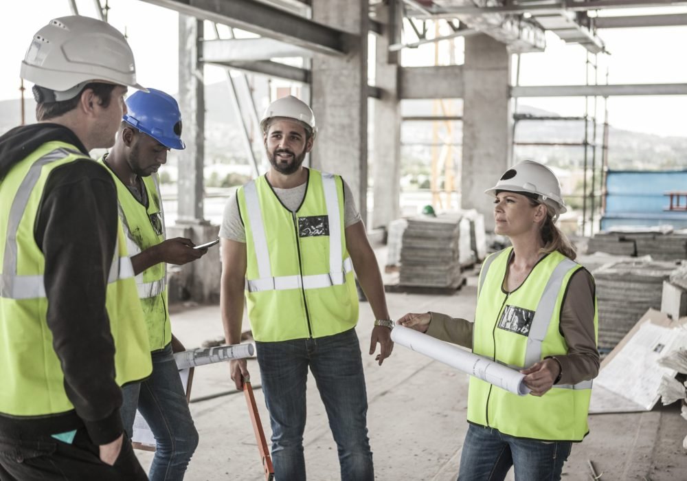 Woman in protective workwear and construction workers in construction site