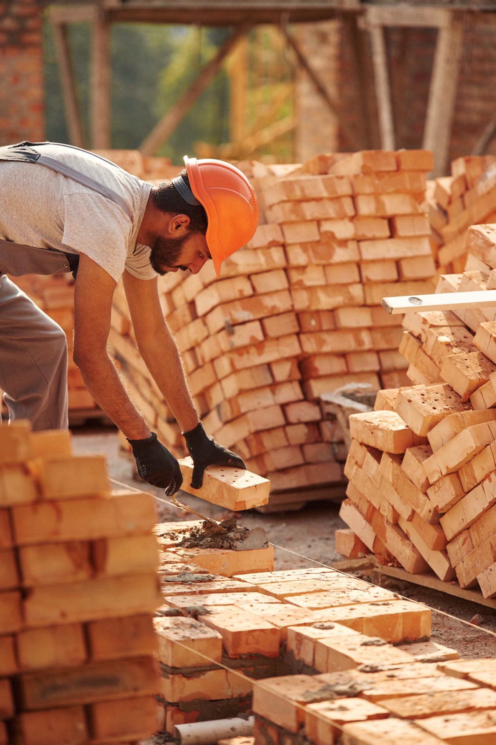 Bunch of bricks. Placing them. Handsome Indian man is on the construction site.