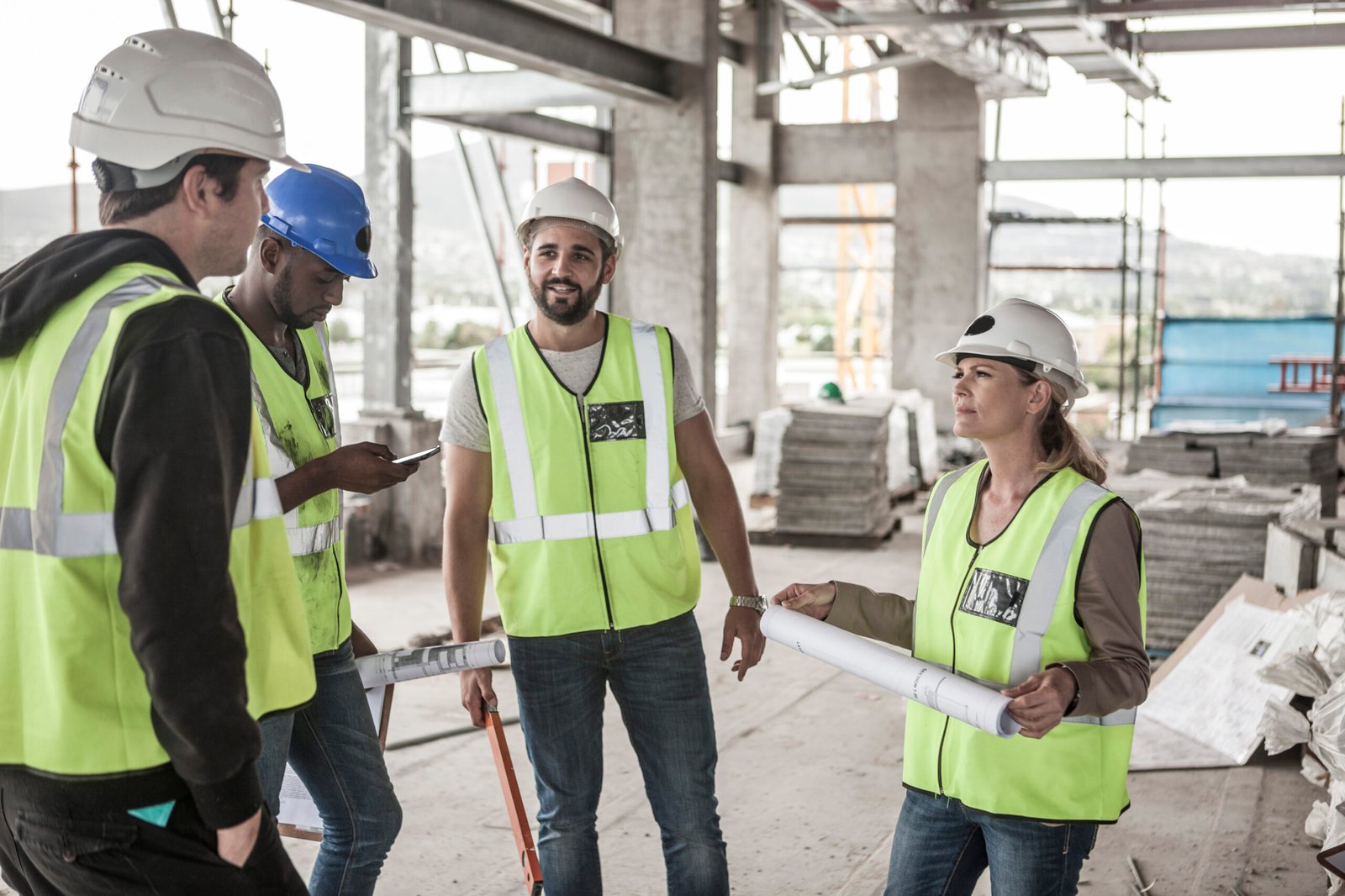 Woman in protective workwear and construction workers in construction site